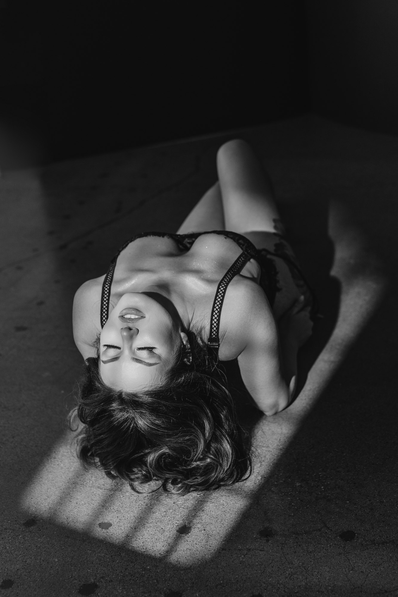 Editorial black lingerie portrait with dramatic striped window light