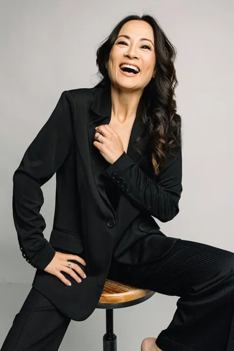 Boise branding photographer — laughing woman in black blazer on stool, J Renee Studios